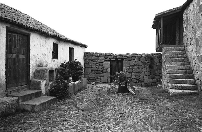 Patio-serventía empedrado. En la vivienda de la derecha destaca la escalera de piedra que desemboca en una galería realizada en madera que hace de antesala al piso superior. Icor, Arico, Tenerife (foto: Carlos A. Schwartz).